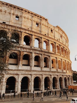 Iconic view of the Colosseum in Rome, Italy, at sunset with tourists outside. by Mark Neal