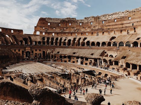 View of the iconic Colosseum in Rome with tourists exploring the ancient amphitheater. by Mark Neal