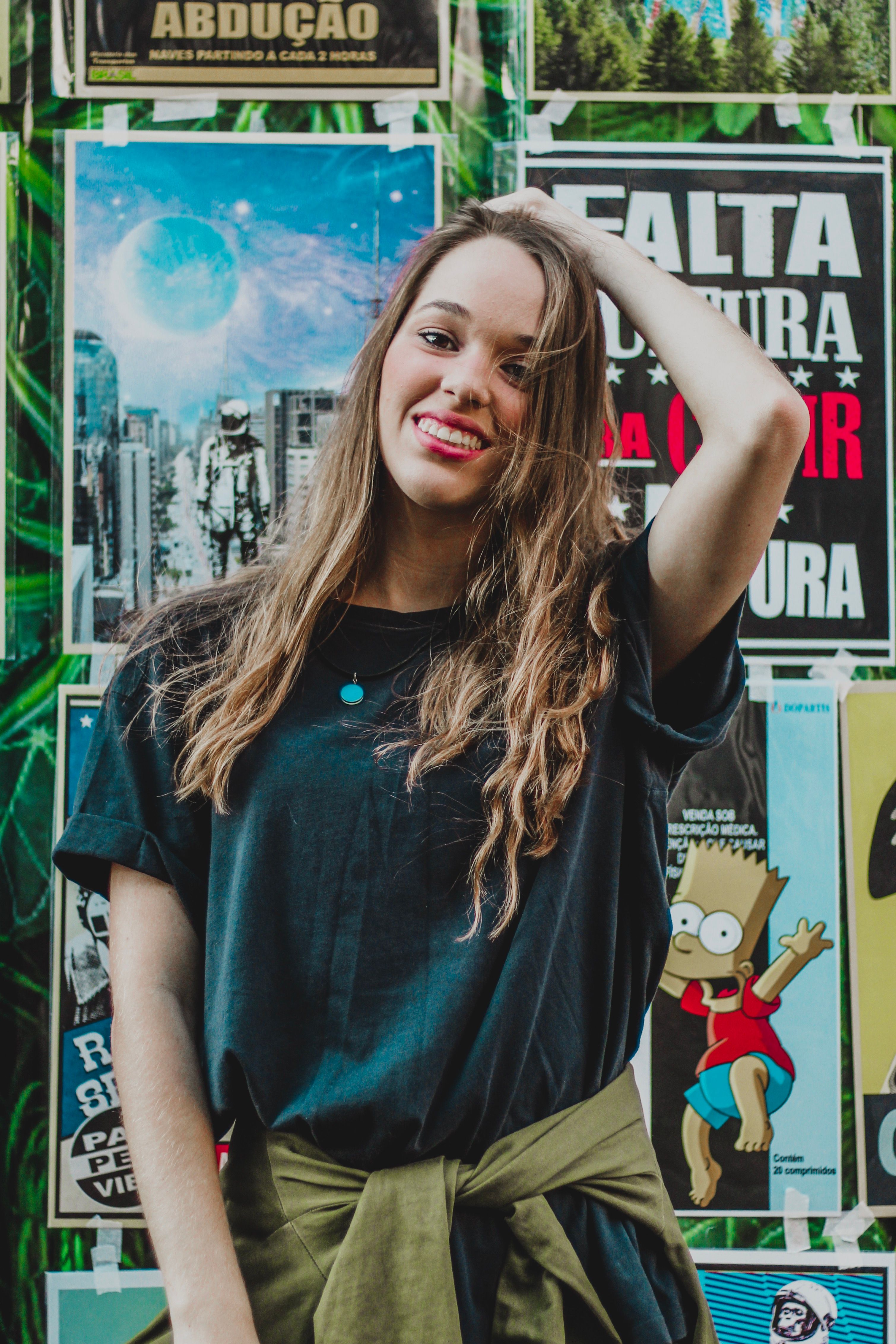Trendy young woman posing against a colorful backdrop of posters, exuding a joyful and casual vibe.