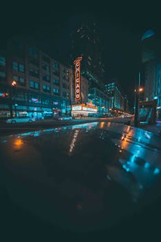 夜间，芝加哥城市街道上，标志性的剧院招牌灯光映照在潮湿的人行道上