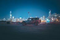 一辆吉普车停在夜晚的城市中，照亮的天际线捕捉到了城市的本质