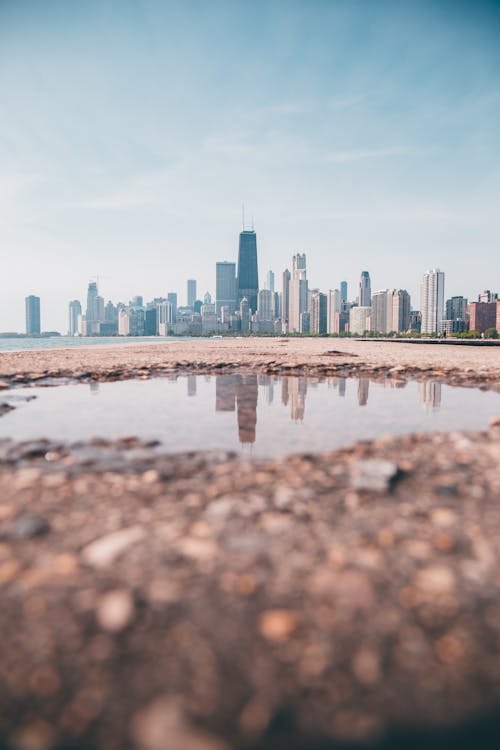 Reflection of Cityscape on Puddle of Water