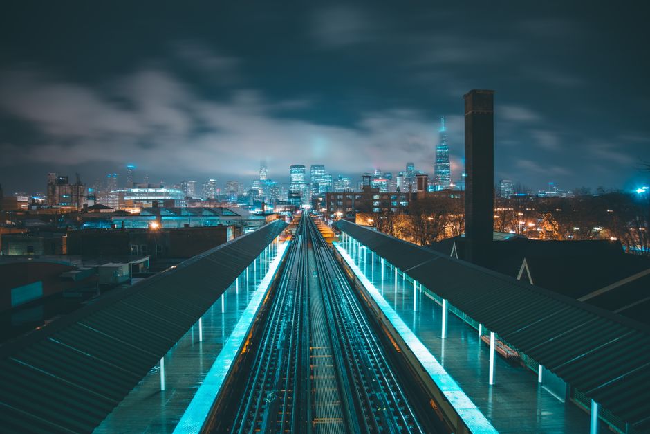 Stunning cityscape at night with illuminated skyscrapers and railway tracks leading into the city.