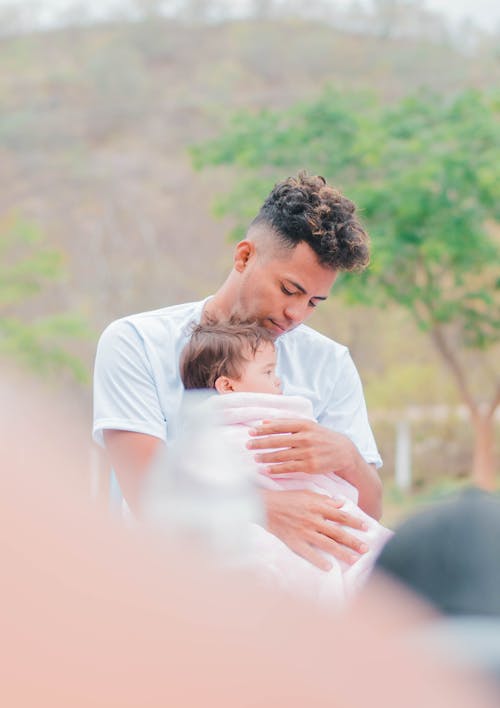 Pria Berkemeja Putih Menggendong Bayi Dengan Handuk