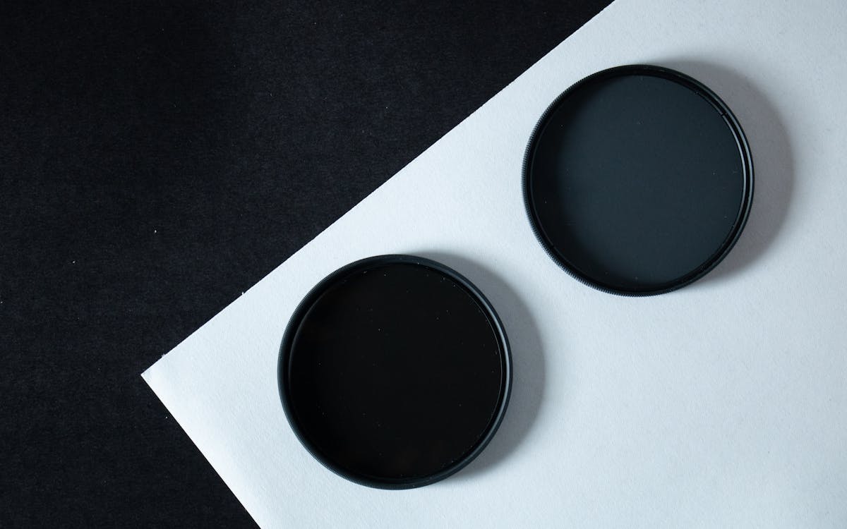 A modern minimalist photo of two black circular filters on contrasting paper for design and technology concepts.
