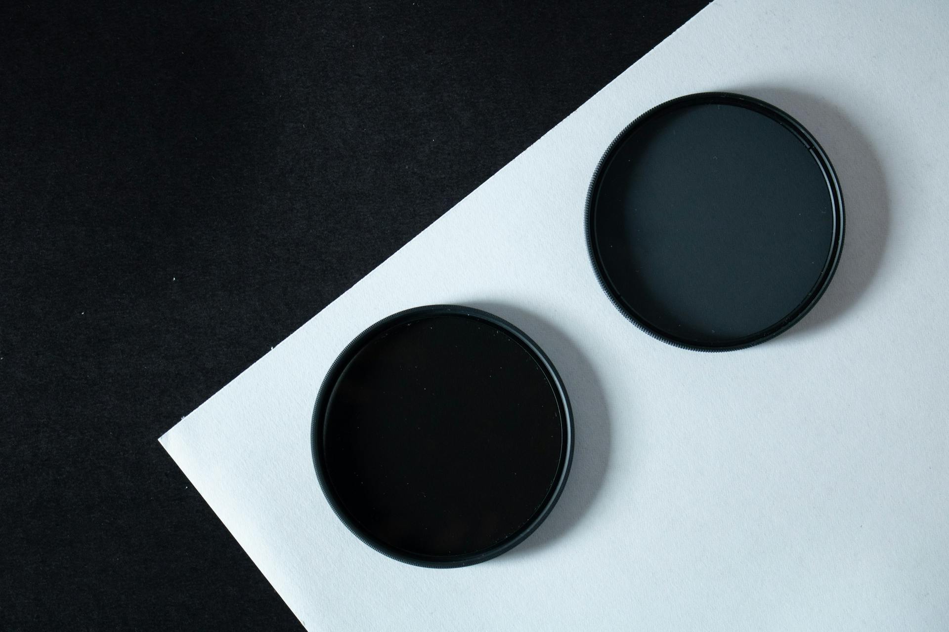 A modern minimalist photo of two black circular filters on contrasting paper for design and technology concepts.