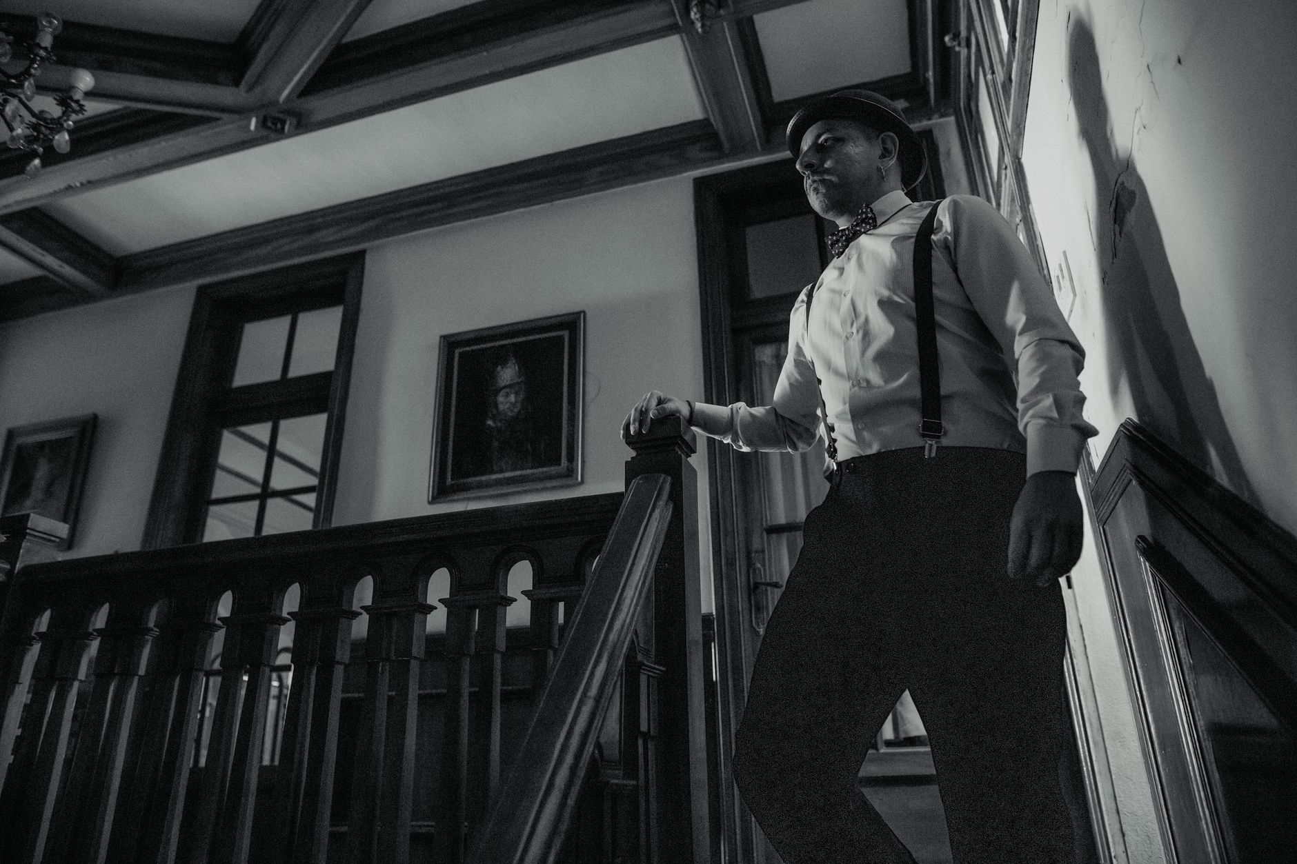 Black and white photo of a man in vintage attire standing on a staircase. Captured in Buenos Aires.
