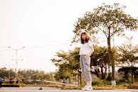 阳光明媚的日子里，一位穿着休闲装的时尚年轻女子在户外摆姿势