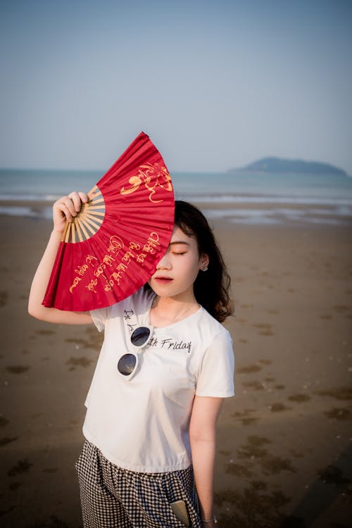 Foto Van Een Vrouw Op Het Strand Met Handventilator Die Een Deel Van Haar Gezicht Verbergt