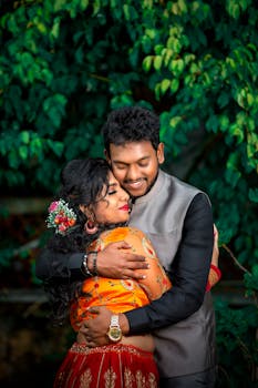 一对身着传统服装的快乐夫妇在户外充满活力的绿叶包围下深情拥抱