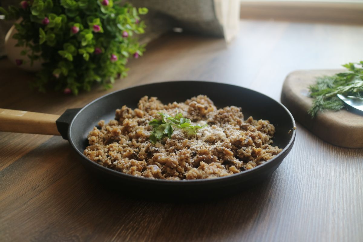 Cooked minced meat with herbs in a black skillet, ready to portion