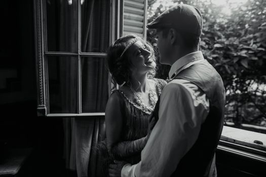 Charming black and white shot of a vintage-styled couple sharing a moment by a window in Buenos Aires.