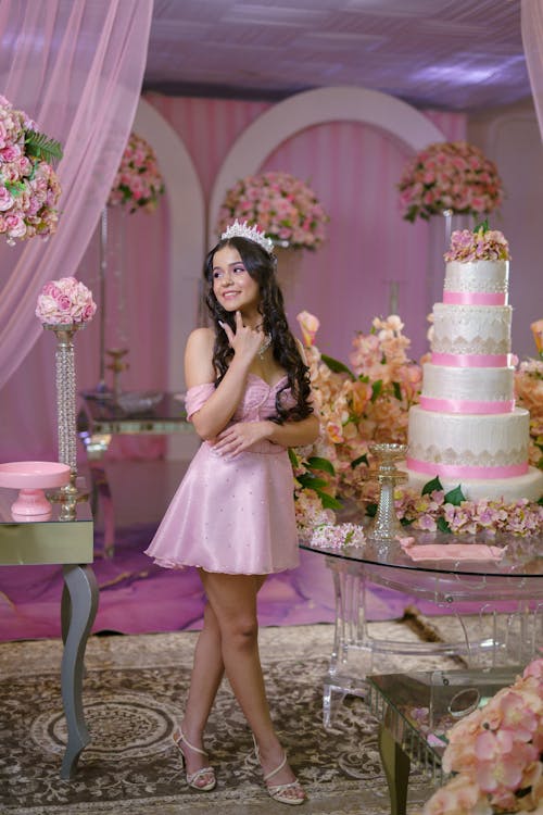 A woman in a pink dress standing in front of a cake