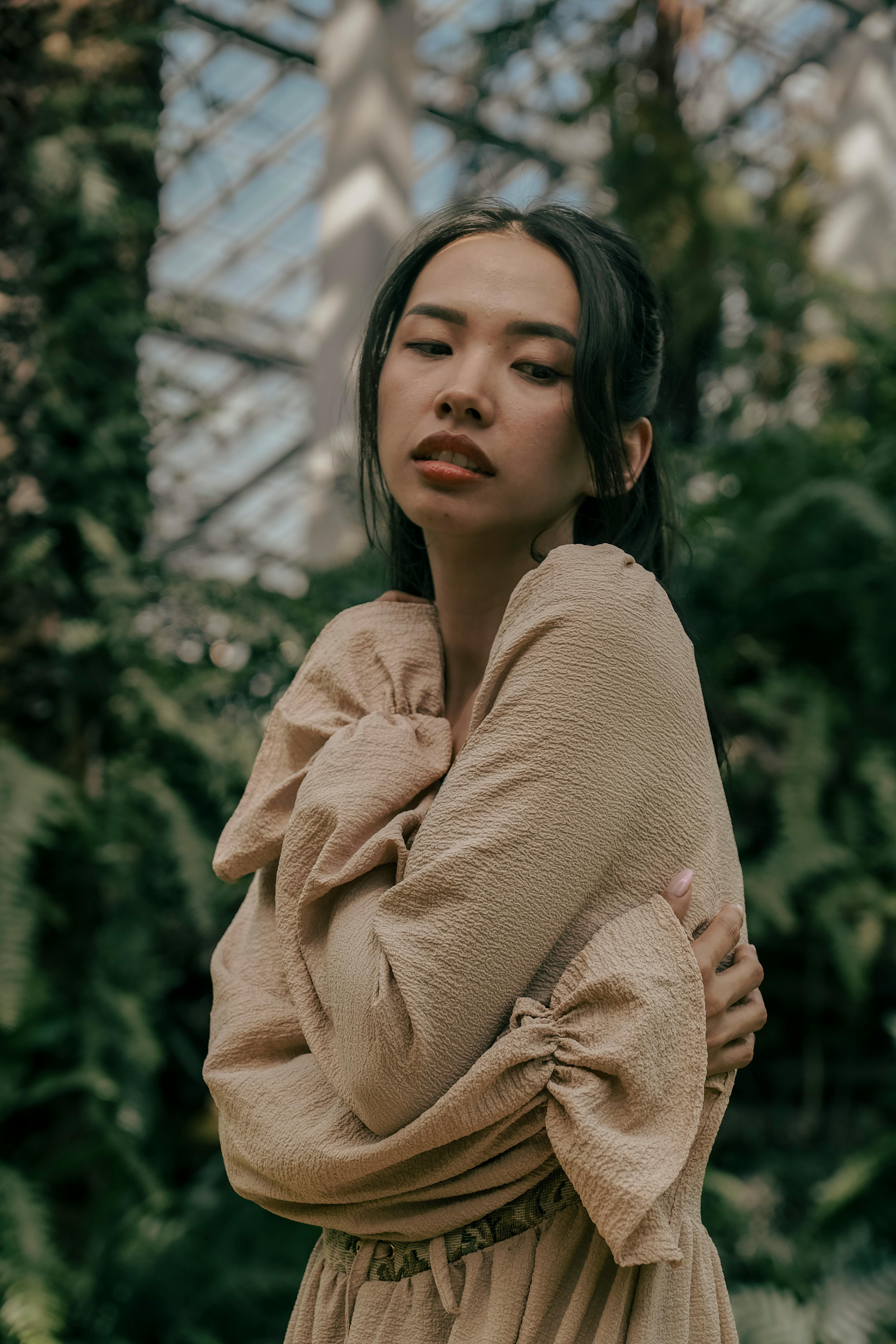 moody vintage woman hugging herself in greenhouse