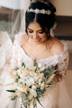 Bride in lace wedding dress holding a beautiful bouquet, smiling and looking down, on her wedding day.