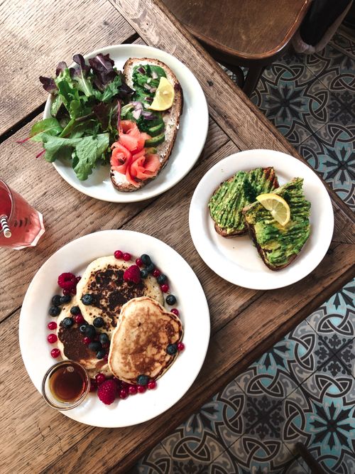 Free Delicious brunch with avocado toast, pancakes, and fresh salad on a rustic table. Stock Photo