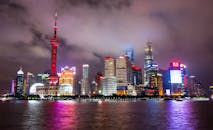 上海的天际线灯火通明，倒映在夜晚的海滨景色中