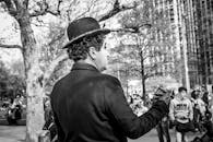 街头表演者身着查理·卓别林的黑白服装，在户外娱乐人群