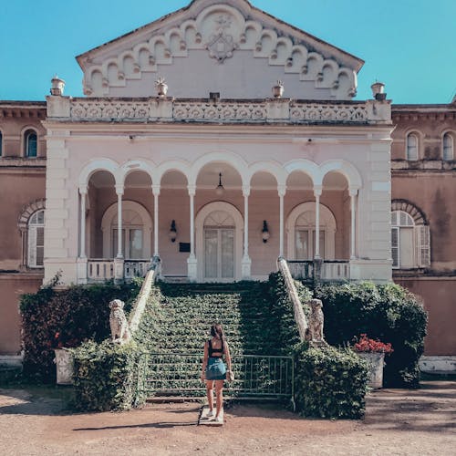 Woman Standing in Front of White Concrete House