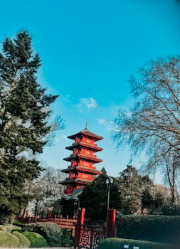 蔚蓝的天空下，一座充满活力的红色高塔矗立在树木繁茂的环境中，营造出宁静的氛围