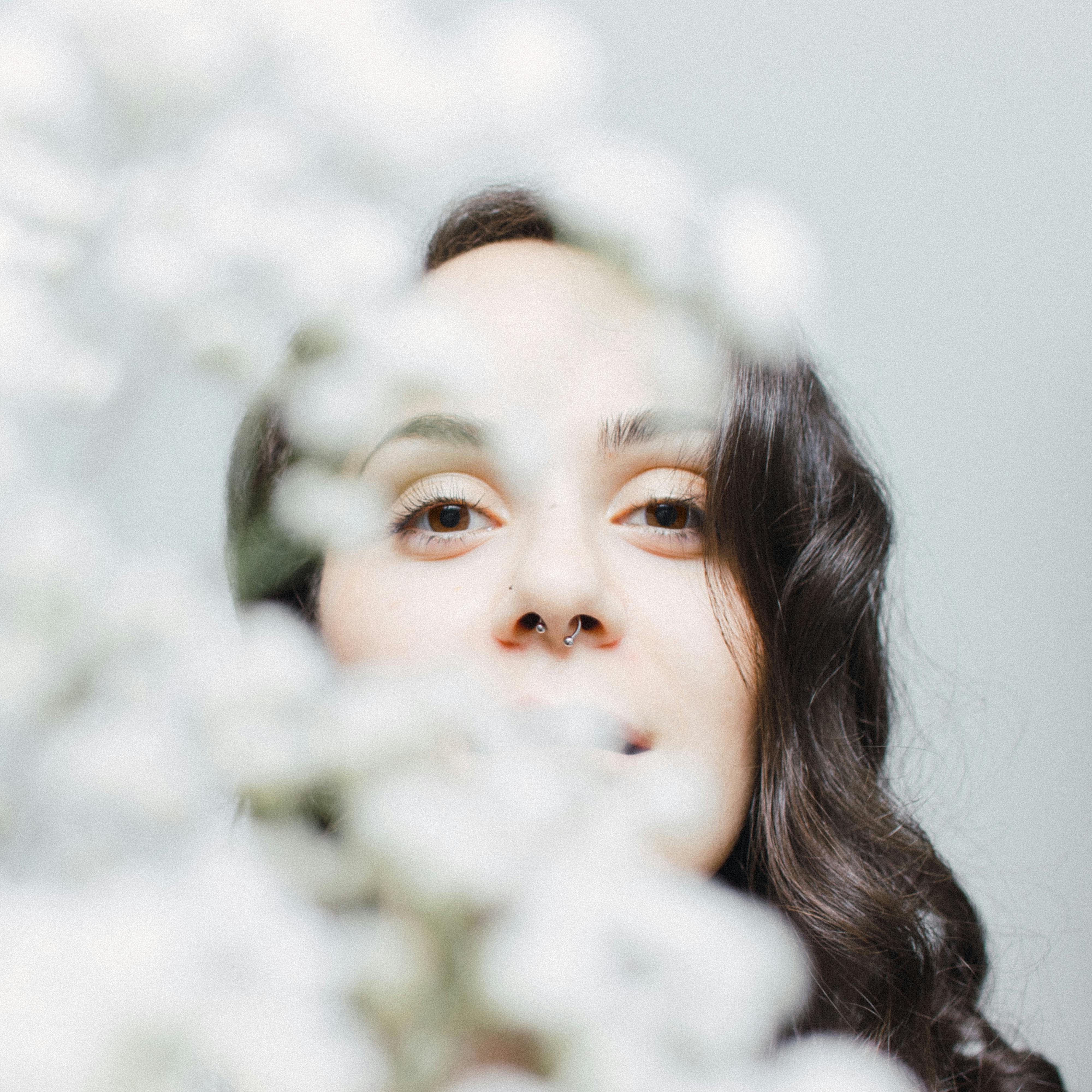 一位戴着鼻环的女人的艺术肖像，部分被白花遮挡