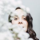 一位戴着鼻环的女人的艺术肖像，部分被白花遮挡