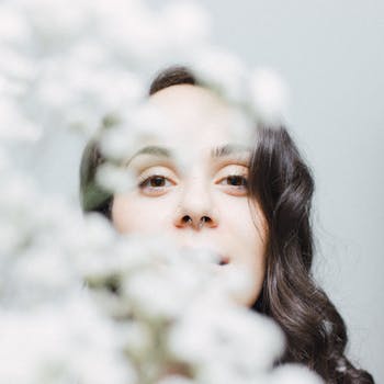 一位戴着鼻环的女人的艺术肖像，部分被白花遮挡