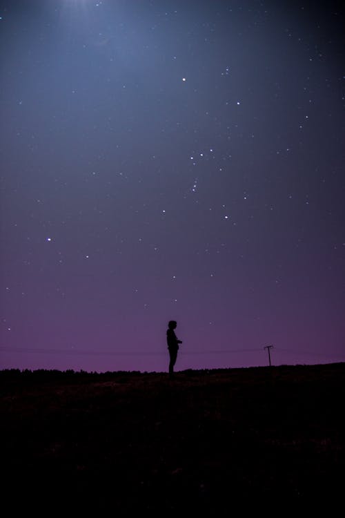Silhouette of Man Standing on Hill Under Starry Night