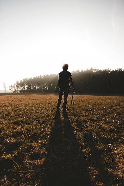 Silhouette of Man Standing on Grass Field 