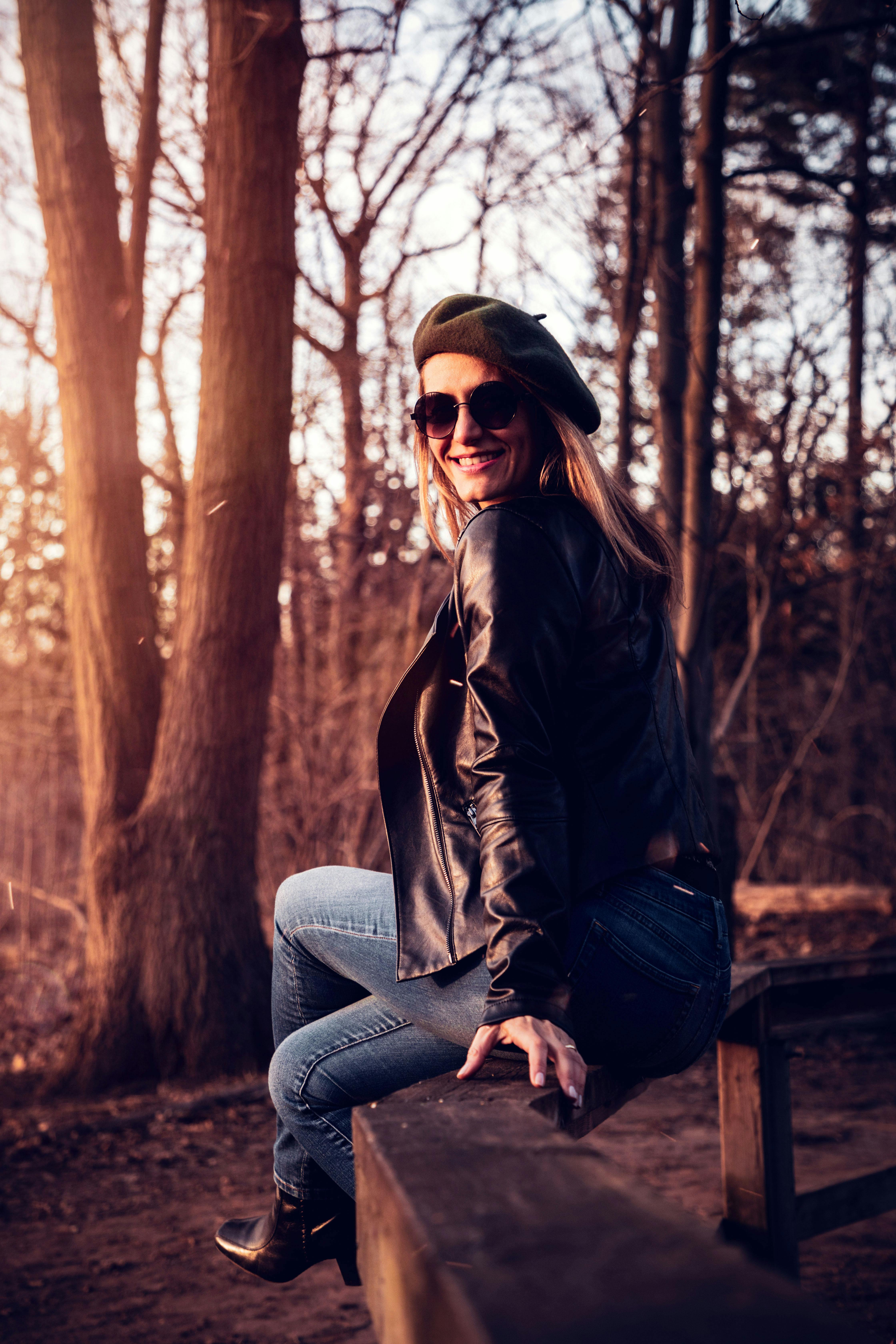 在安大略省伯灵顿的森林中，一名身穿皮夹克、头戴贝雷帽的女子正在欣赏日落