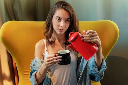 Photo of a Woman Pouring Pitcher on Cup