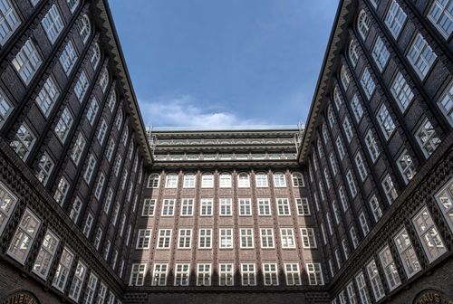 Free Looking up at a historic brick building with symmetrical windows and a bright blue sky. Stock Photo