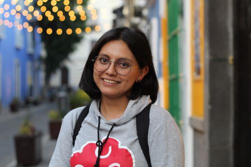 Free A woman smiling in a hoodie with colorful urban lights and buildings in the background. Stock Photo
