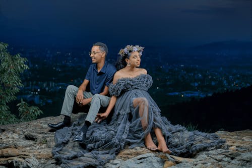 A man and woman sitting on a rock at night
