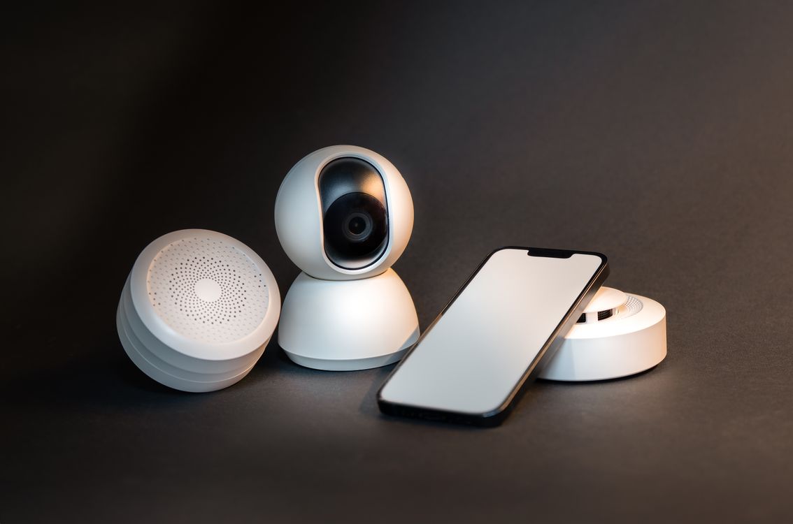 Pametni telefon s modernim smart home uređajima na sivoj pozadini