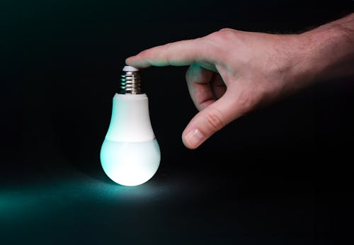 Hand holding glowing light bulb.