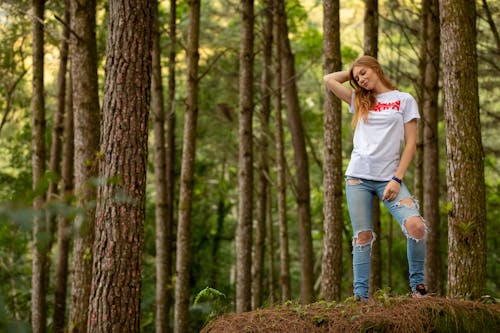 女人穿著白襯衫在棕色的樹旁擺姿勢