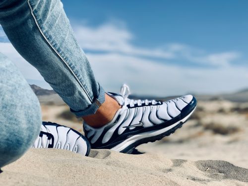 Free Close-up of sneakers and jeans on sandy beach, symbolizing leisure and adventure. Stock Photo