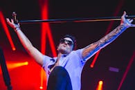 在明亮的舞台灯光下，表演者手持麦克风支架，这是音乐会上激动人心的时刻