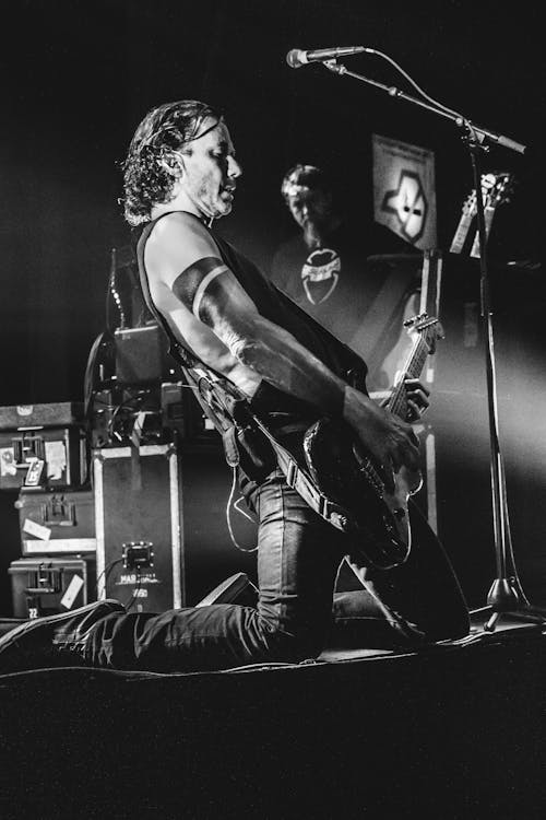 Man Kneeling While Playing Guitar