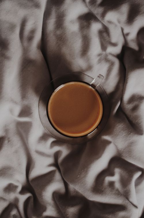 Free Top view of a coffee cup resting on a gently wrinkled fabric surface, creating a warm ambiance. Stock Photo