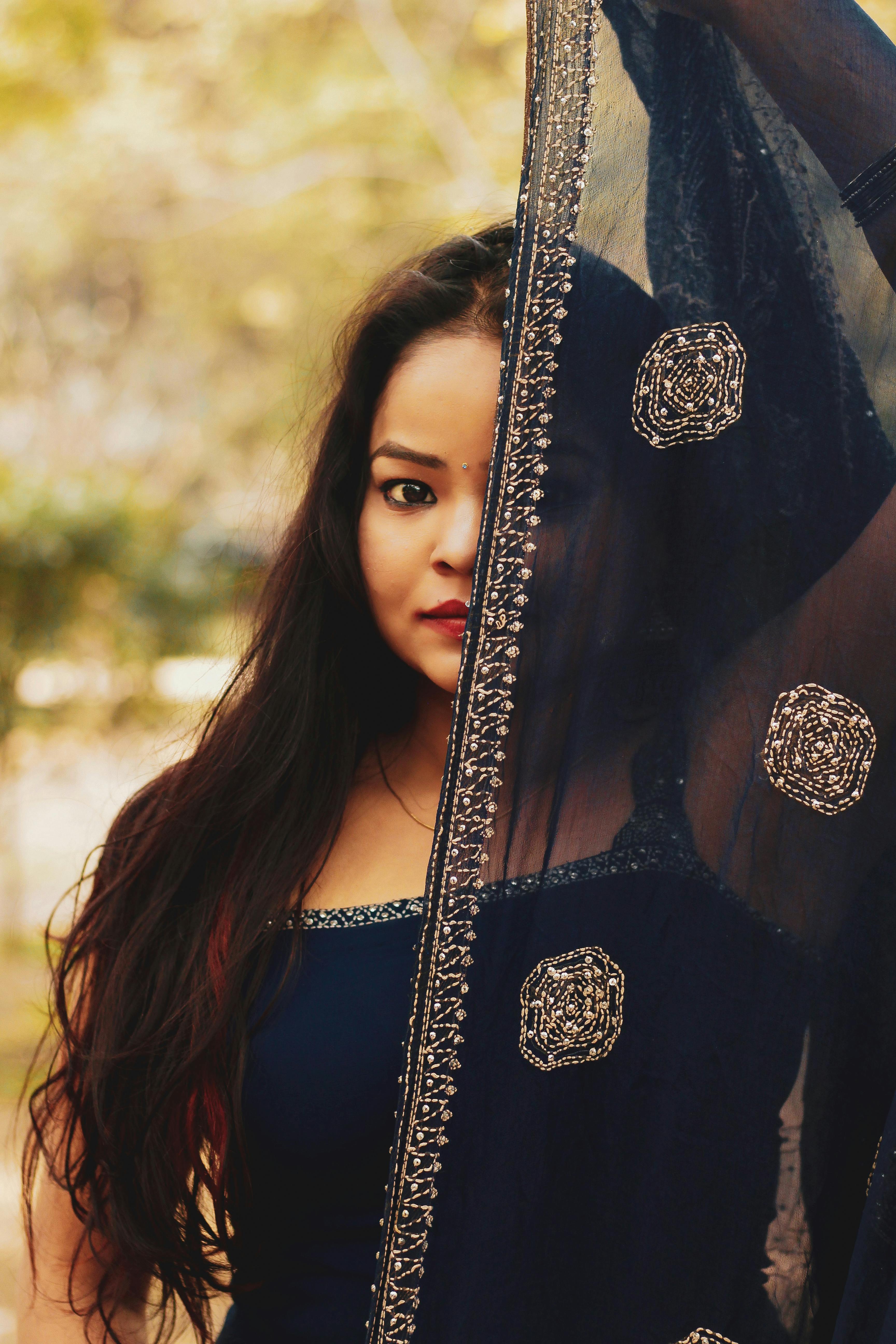 A captivating portrait of a woman in a traditional dress with an embroidered veil outdoors.