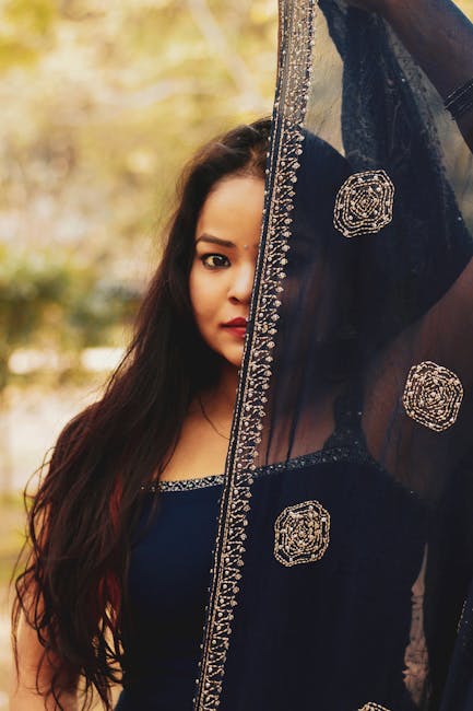 A captivating portrait of a woman in a traditional dress with an embroidered veil outdoors.