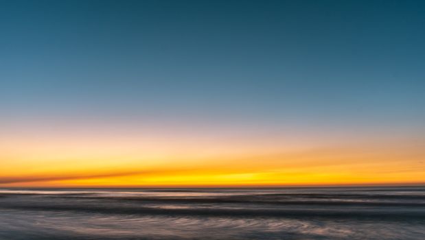 A tranquil ocean view at sunset with colorful skies and calm waters.