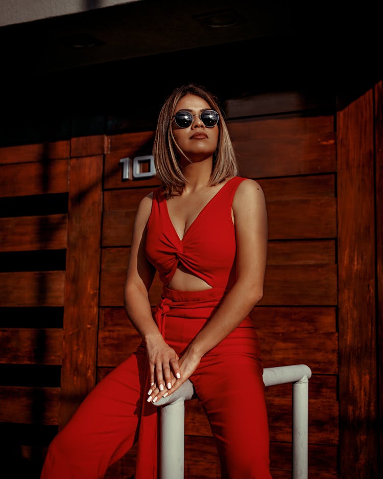 Photo Of Woman In Red Romper Sitting On Metal Rail