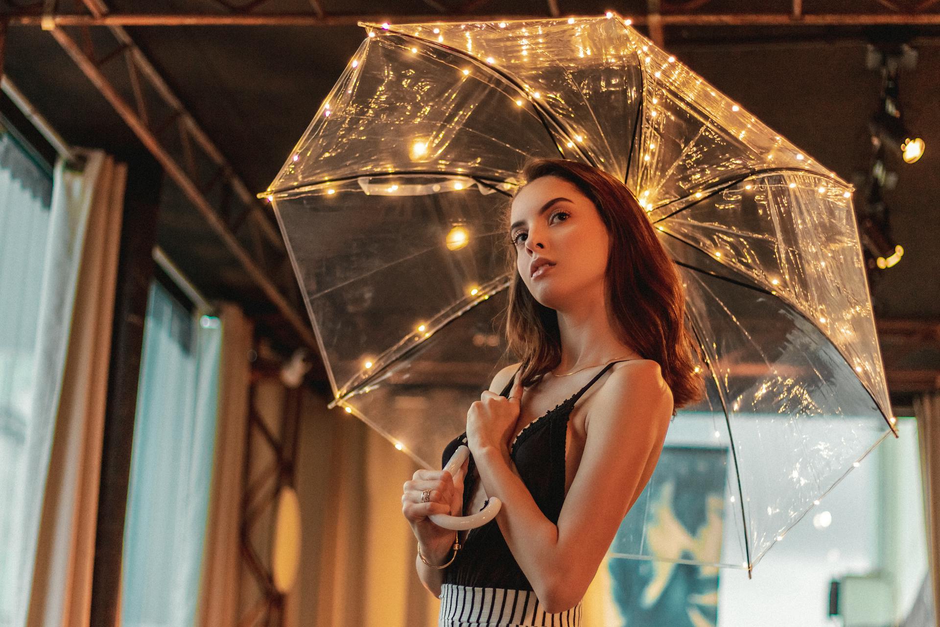 Chic portrait of a woman with a lit umbrella in an indoor setting.