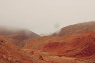红色沙漠风景优美，雾气笼罩的山脉更添神秘氛围