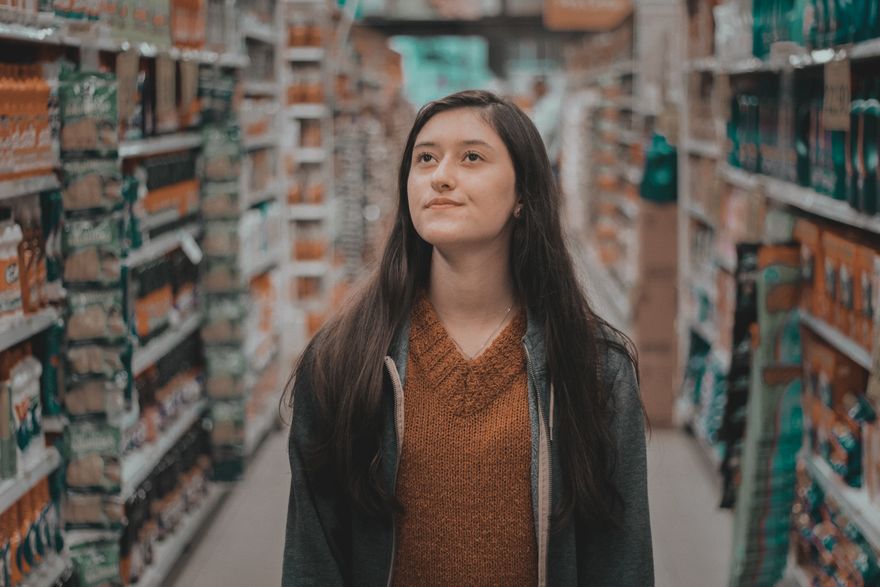 A shopper pausing to read packaging while browsing a grocery aisle — photo by Lucas Percegona on Pexels