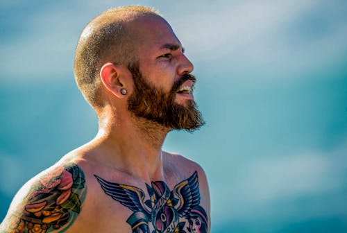 Free Side View Photo of Bearded Shirtless Man With Chest and Arm Tattoos Stock Photo