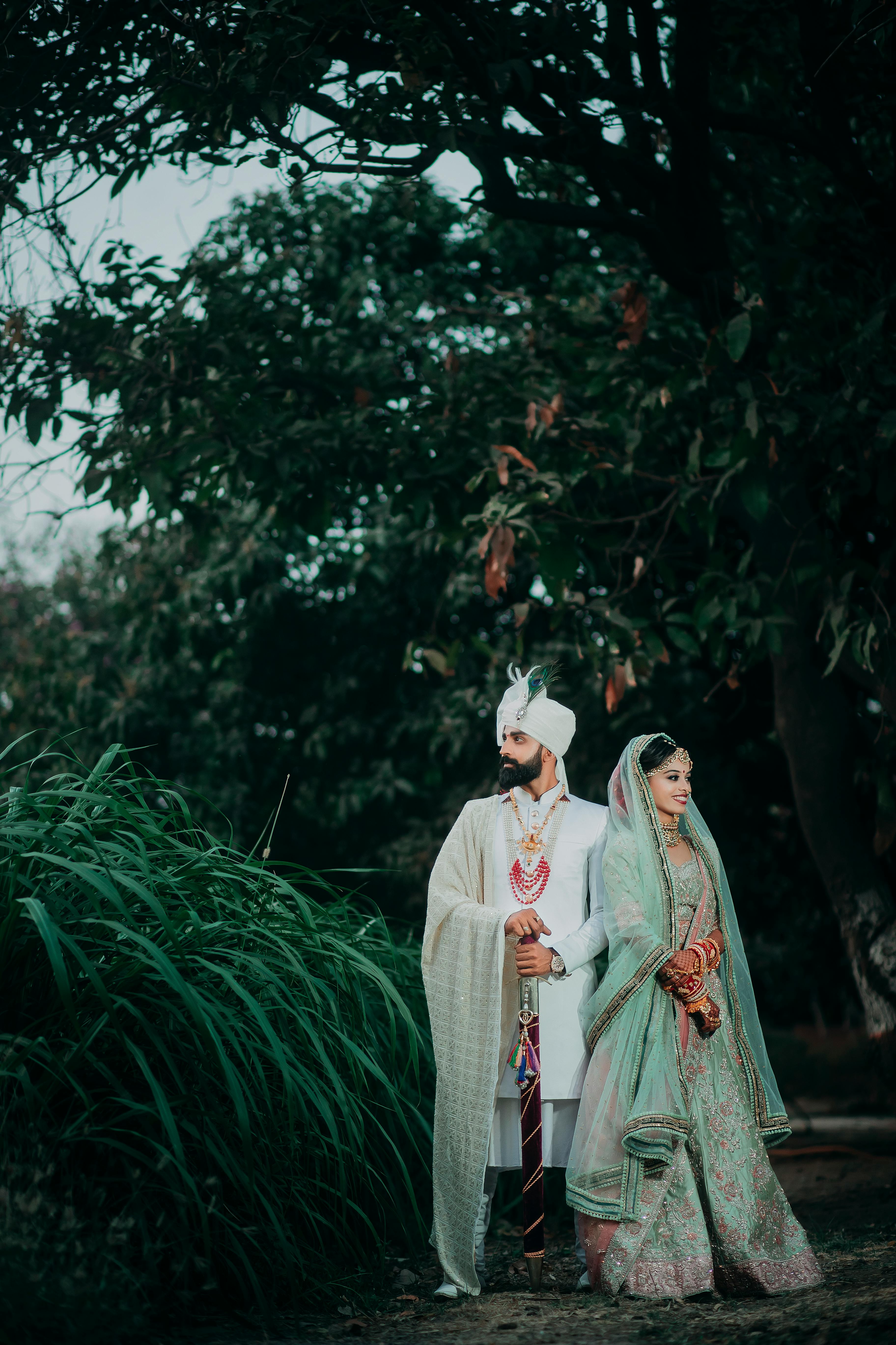 Elegant Indian bride and groom in traditional attire posing outdoors in Surat, India.